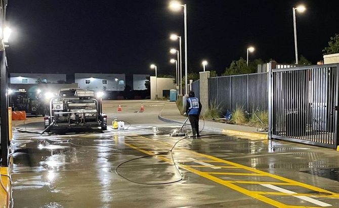 A warehouse is being cleaned at night with a fire hydrant in the foreground.