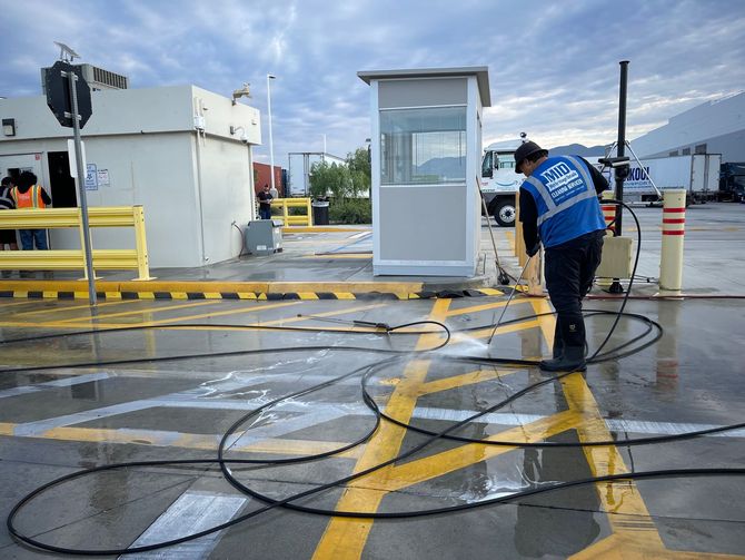A man is cleaning a parking lot with a vacuum cleaner.