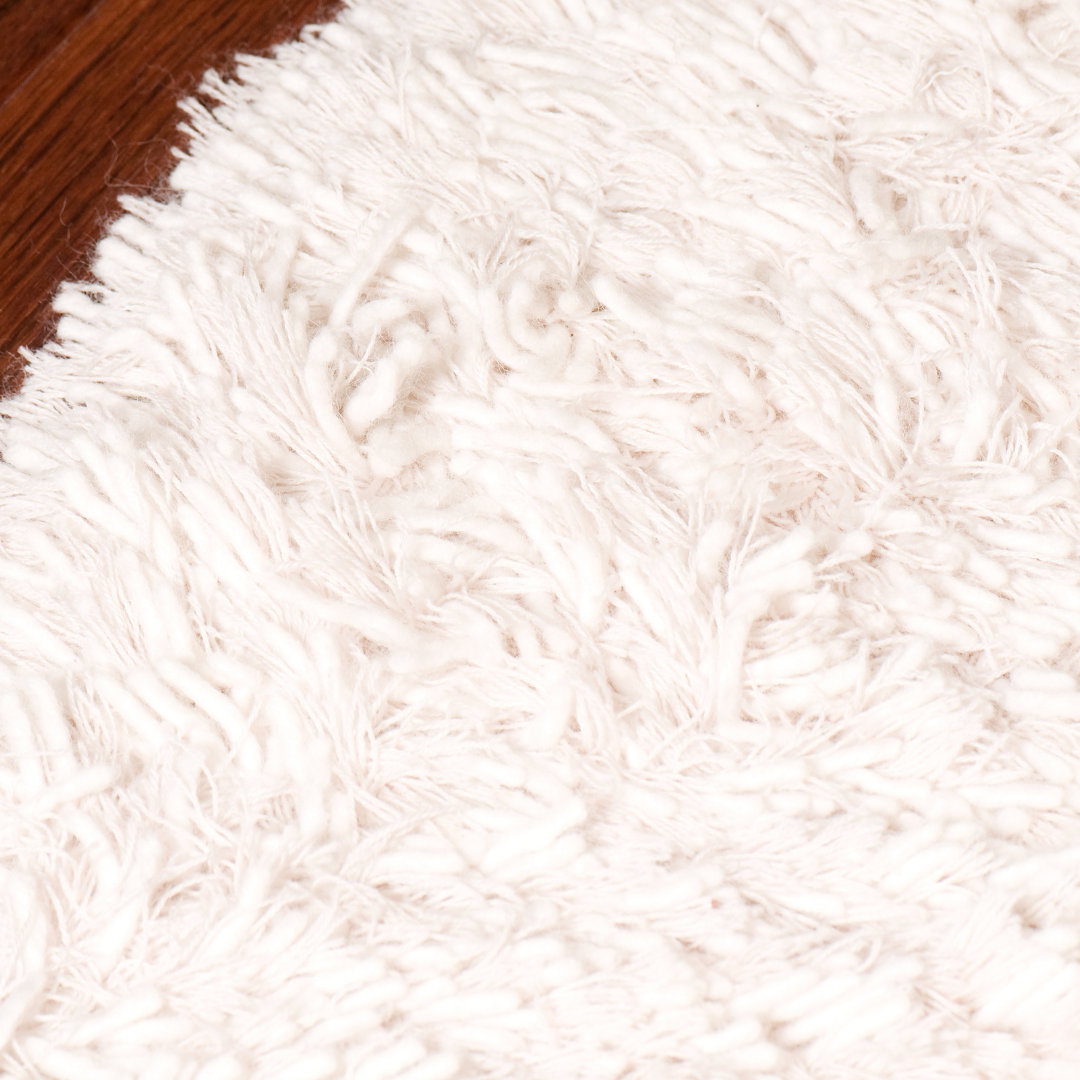 A close up of a white fluffy rug on a wooden floor.