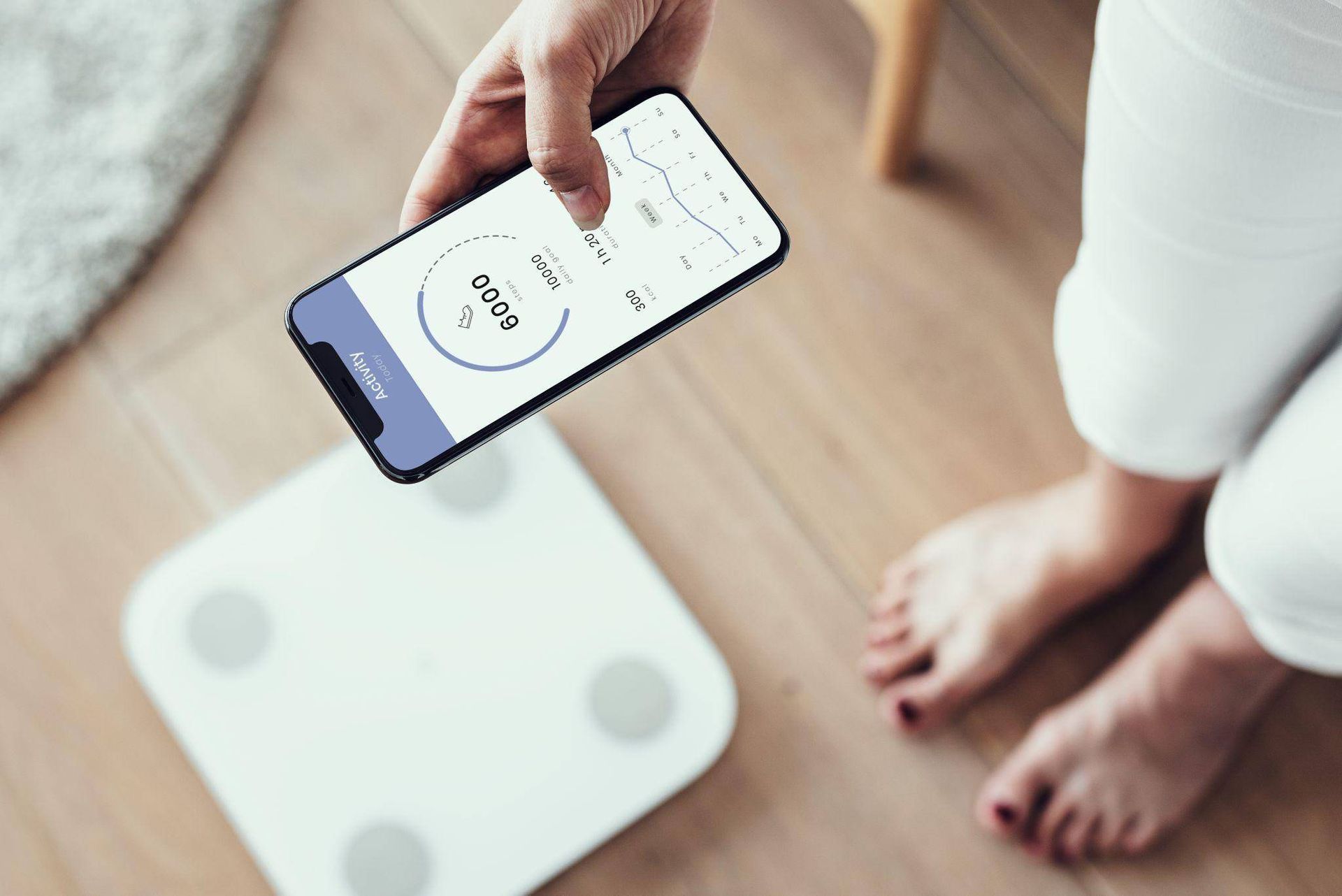A person is using a smart phone to check their weight on a scale.