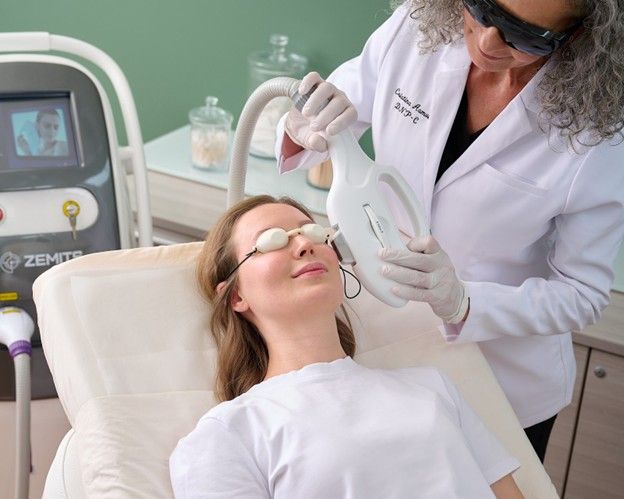 A woman is getting a laser treatment on her face.