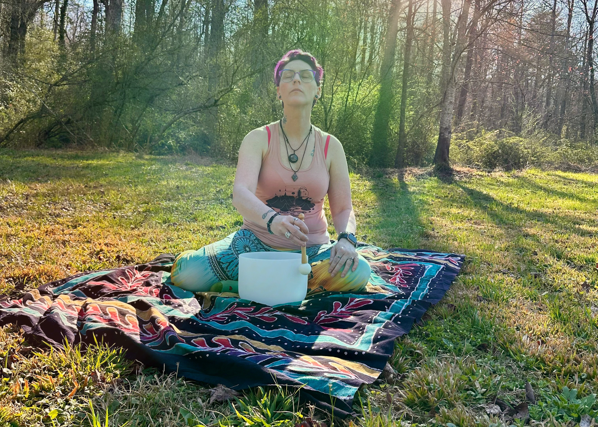 Person cleansing a necklace in a sound bowl on a colorful tapestry.