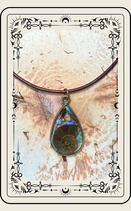 Pendant with ammonite fossil and colorful crystals, set against carved wood background.