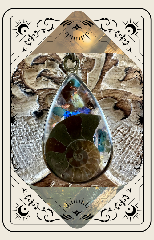 Pendant with ammonite fossil and colorful crystals, set against carved wood background.