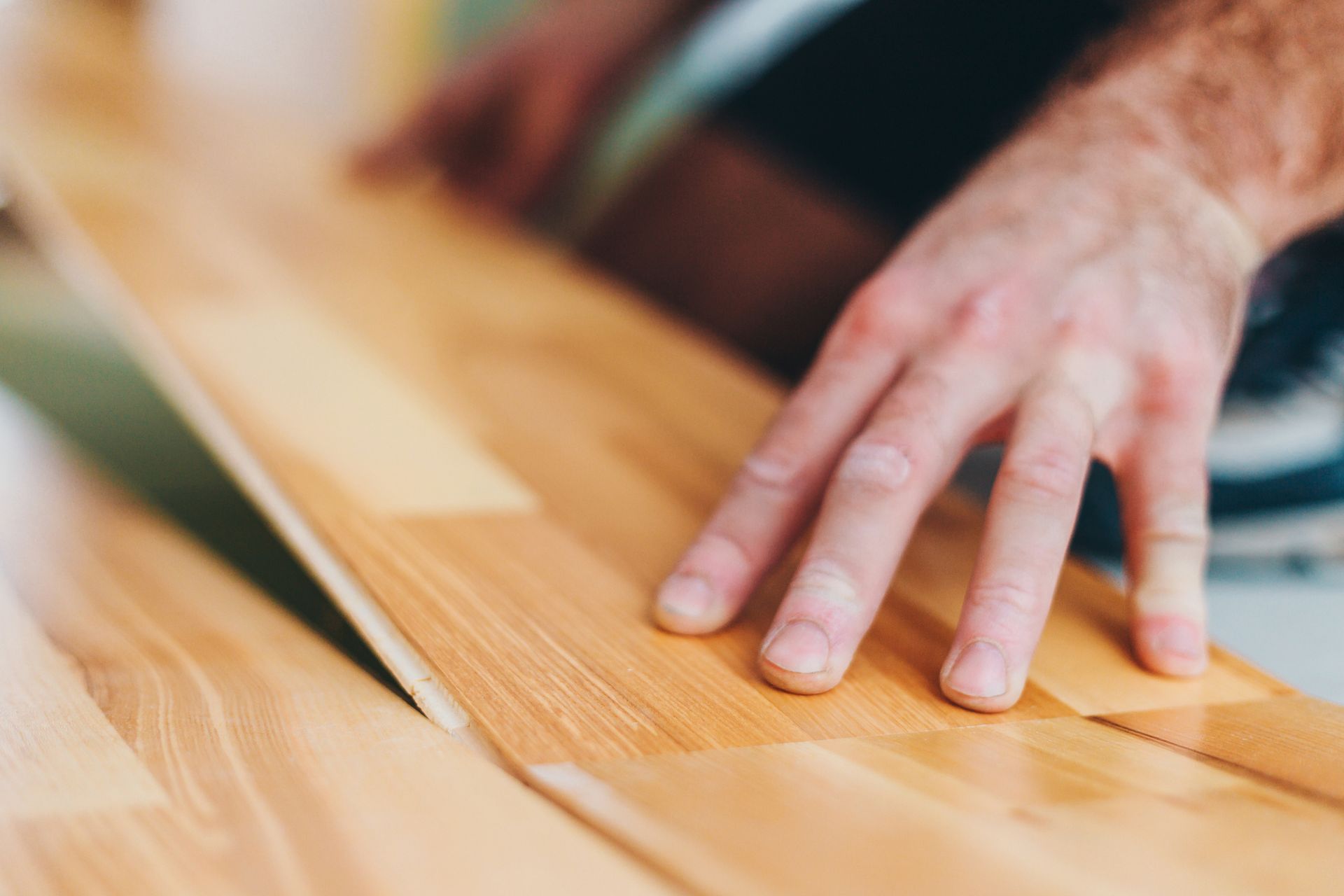 A person's hand on a wood surface for a Wood Floor Installation 