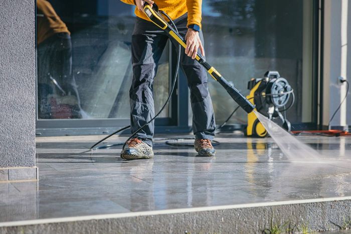 Man Cleaning The Terrace With High Pressure Cleaner — Mt. Holly, NJ — Gcapital Handyman Services LLC Man Cleaning The Terrace With High Pressure Cleaner — Mt. Holly, NJ — Gcapital Handyman Services LLC