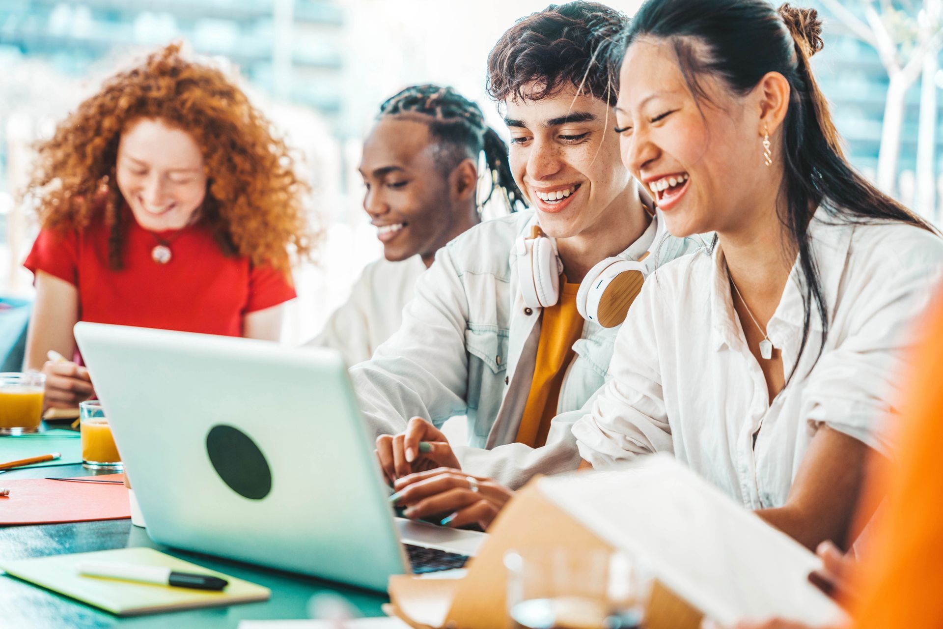 People gathered around a laptop, smiling and working together at a table.