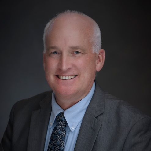 A man in a suit and tie is smiling for the camera.