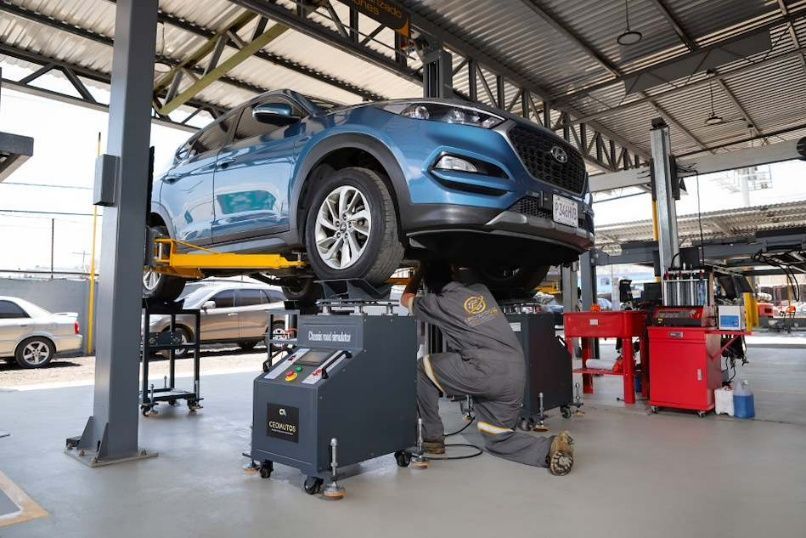 Mecánico trabajando en el motor de un coche con el capó abierto en un taller mecánico.