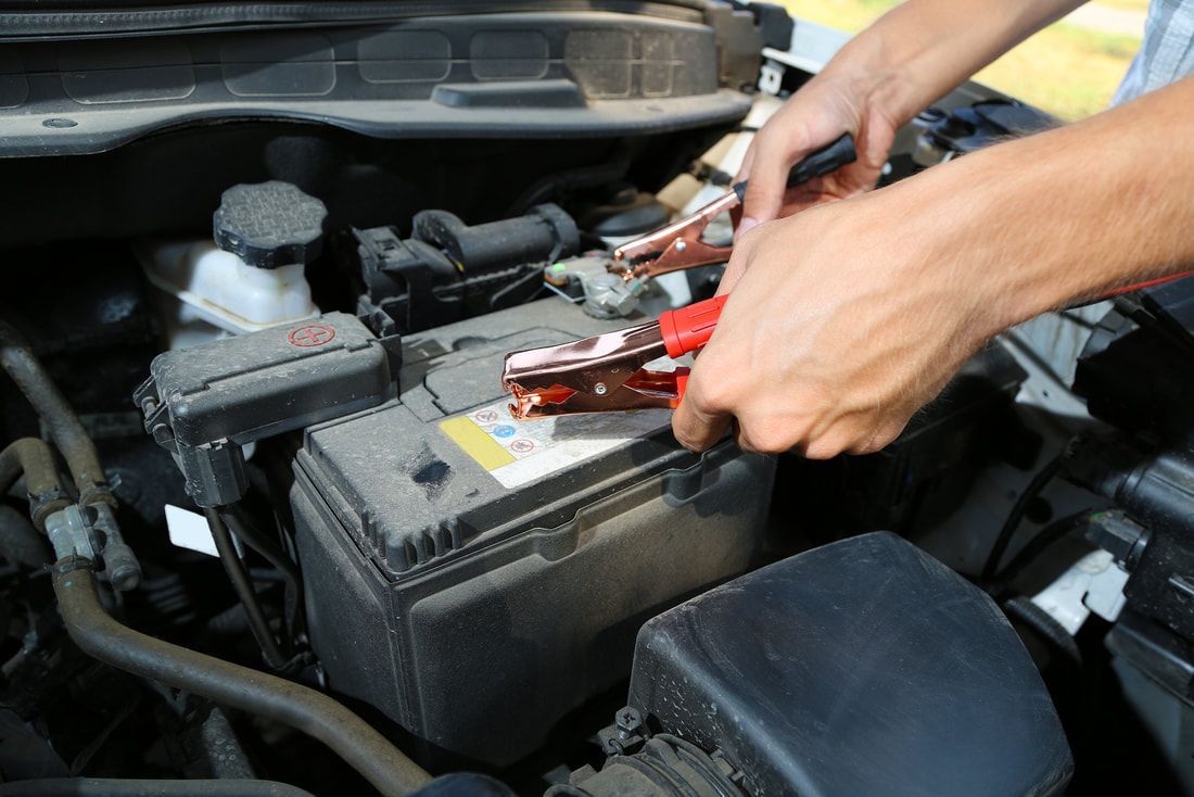 A person is plugging a car battery with jumper cables.
