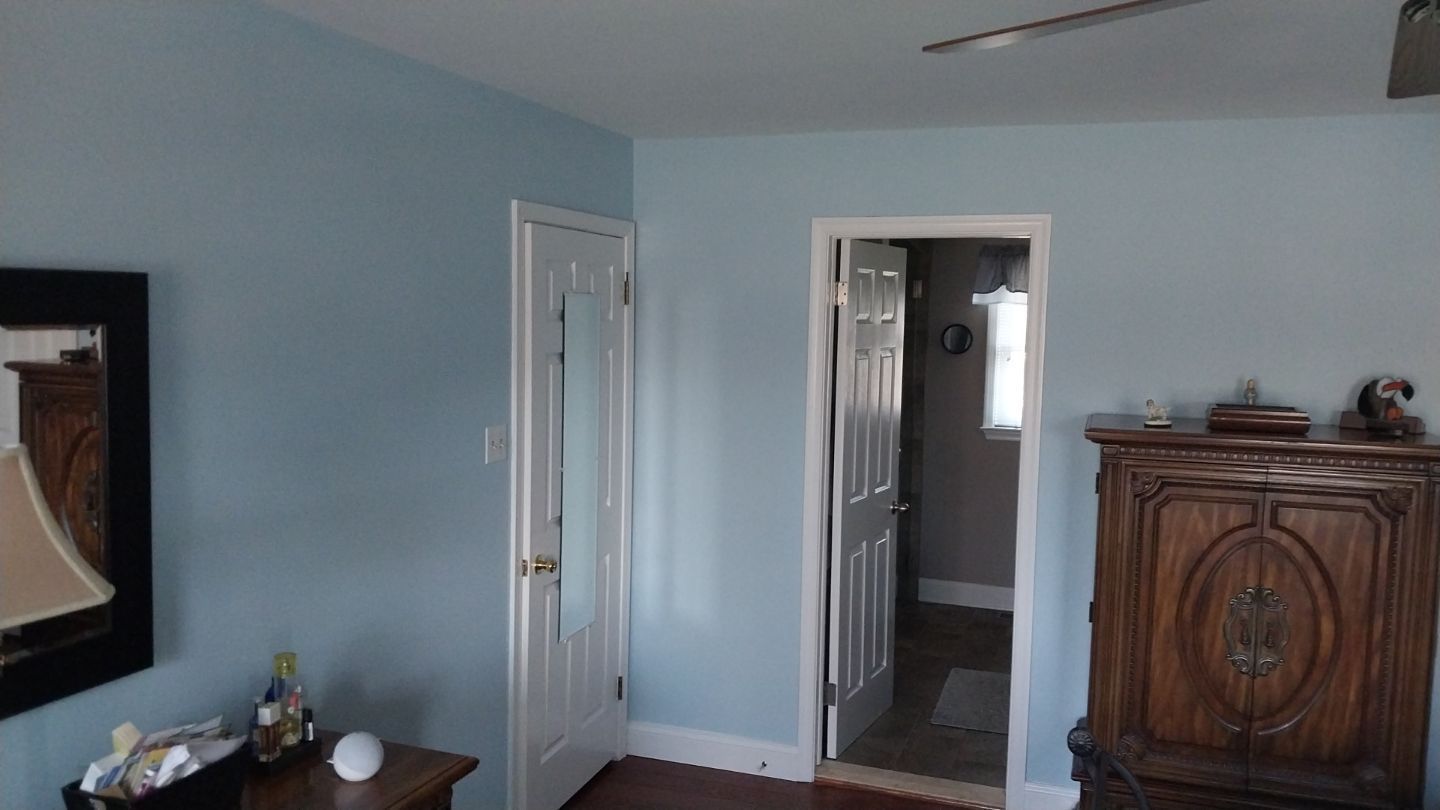 Freshly painted master bedroom with light blue walls, white ceiling, and white bathroom door – after interior painting project in Hatfield, PA.