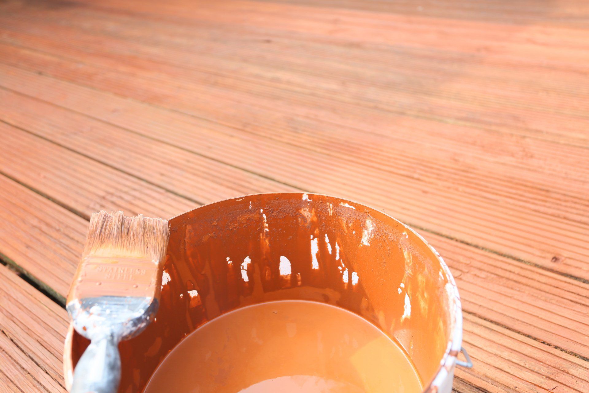 painting, staining or varnishing the outside deck or decking to repair it, with paint brush and bucket.