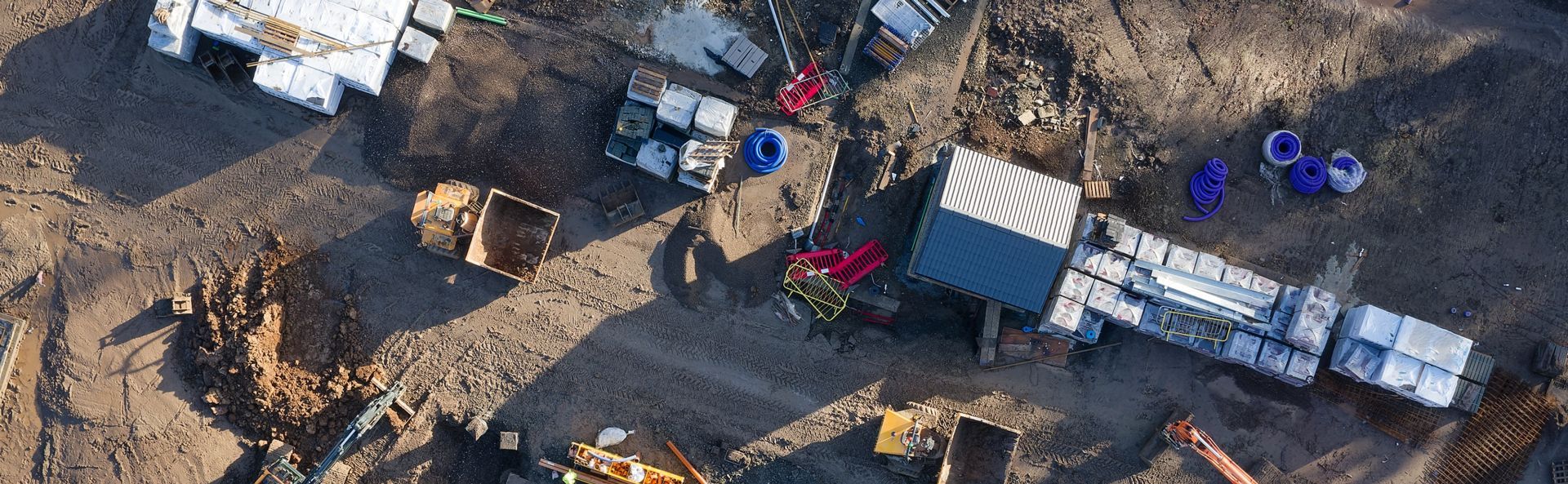 An aerial view of a construction or mining site with heavy machinery, storage containers, and piles of dirt.