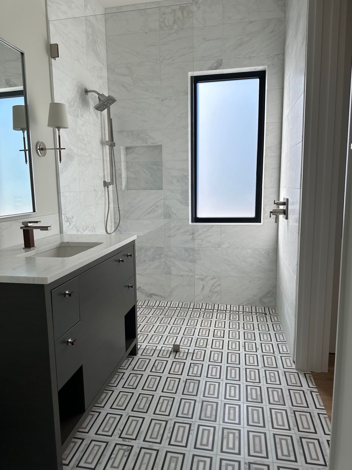 Empty modern living room with hardwood floors and large windows overlooking a blue sky.