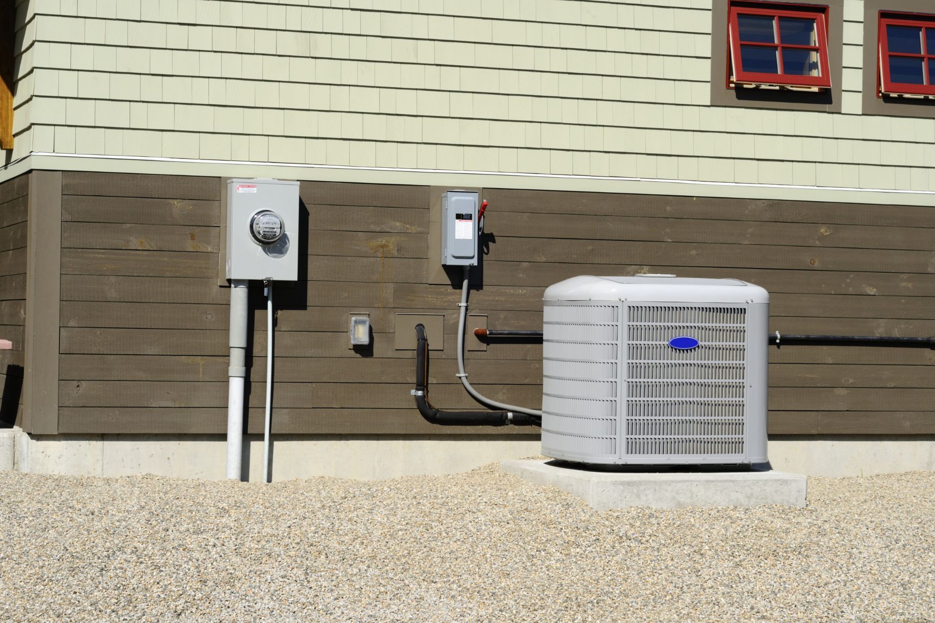 An air conditioning unit next to electrical boxes on a house. AC Installation in Nothville, MI