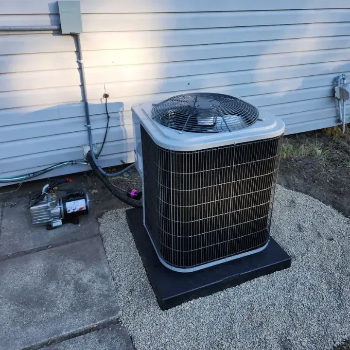 Outdoor air conditioner unit beside a house wall with visible electrical wiring on a concrete pad