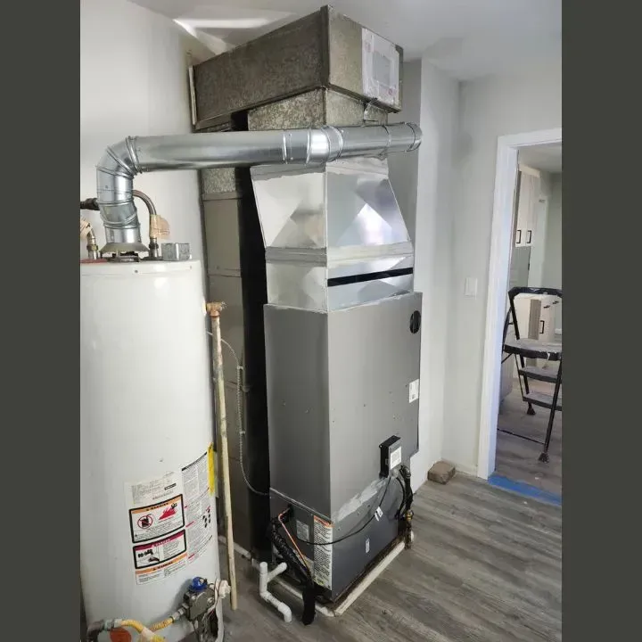 Utility room with a water heater and furnace connected by silver ductwork.