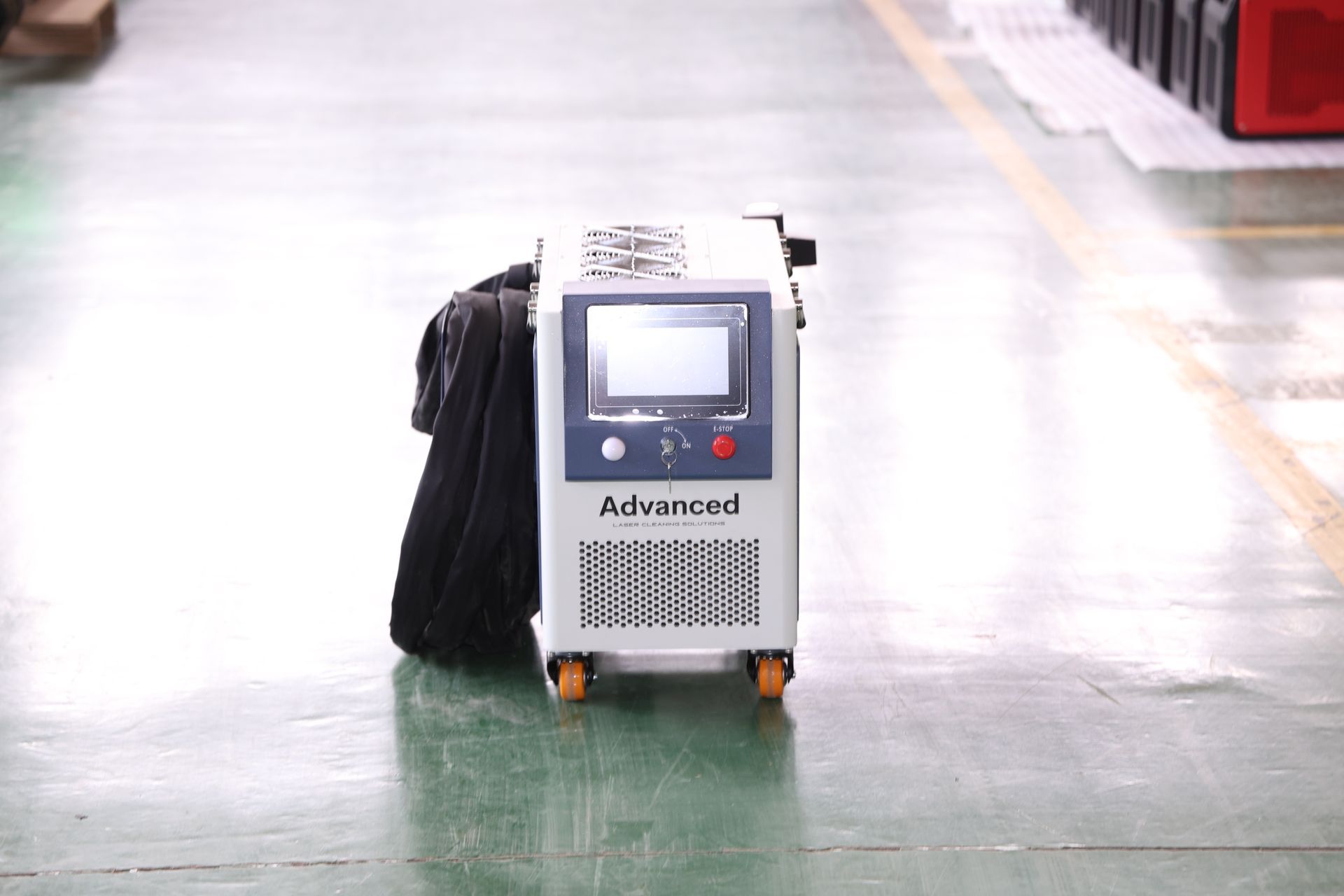 Silver industrial machine on wheels with a screen, in a factory.