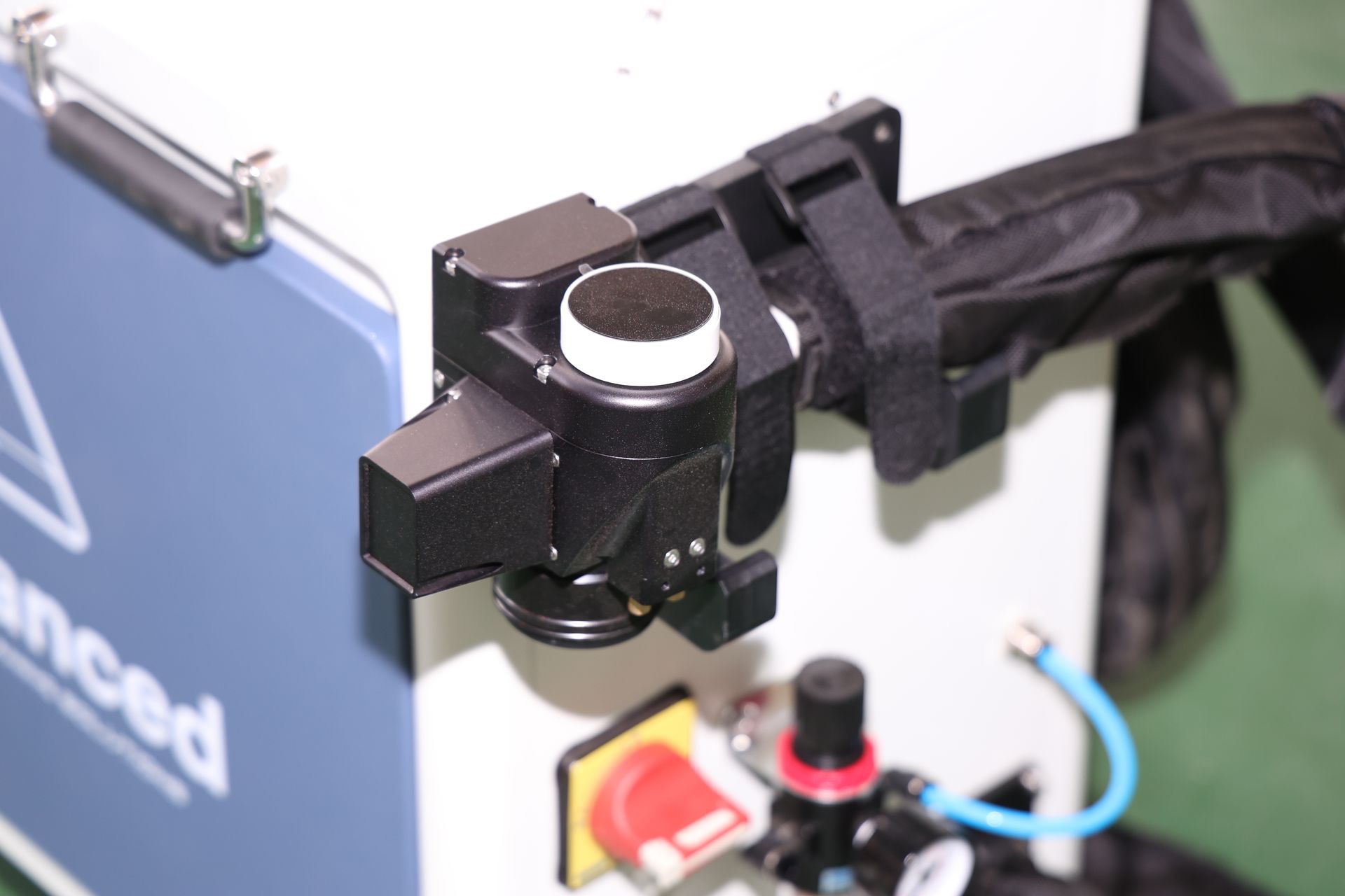 Black and white laser head attached to a machine, next to a control panel.