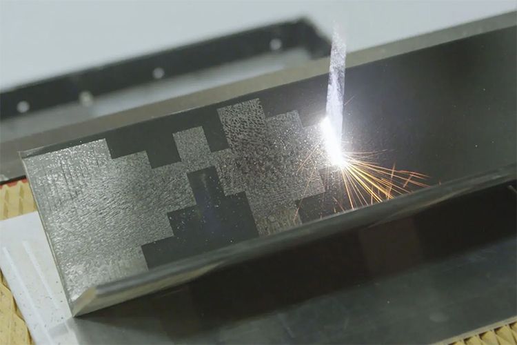 Laser cleaning metal with sparks and geometric pattern.