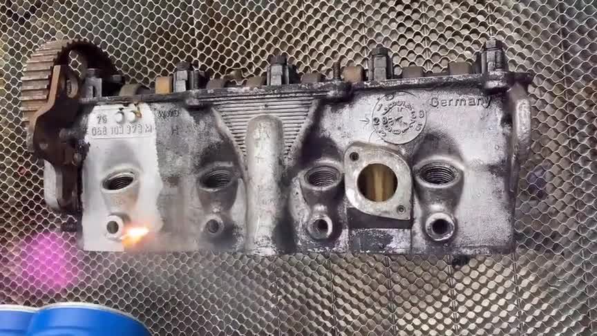 Engine cylinder head being laser cleaned, gray metal, view of ports and stamp 