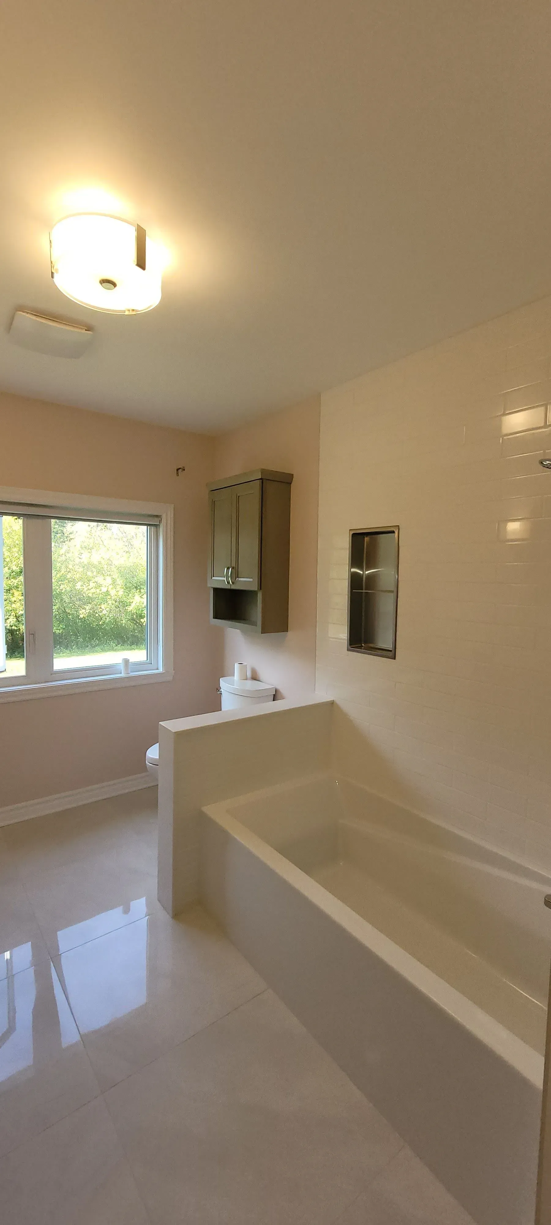 Salle de bain blanche et lumineuse avec fenêtre, meuble-lavabo, miroir et baignoire-douche combinée