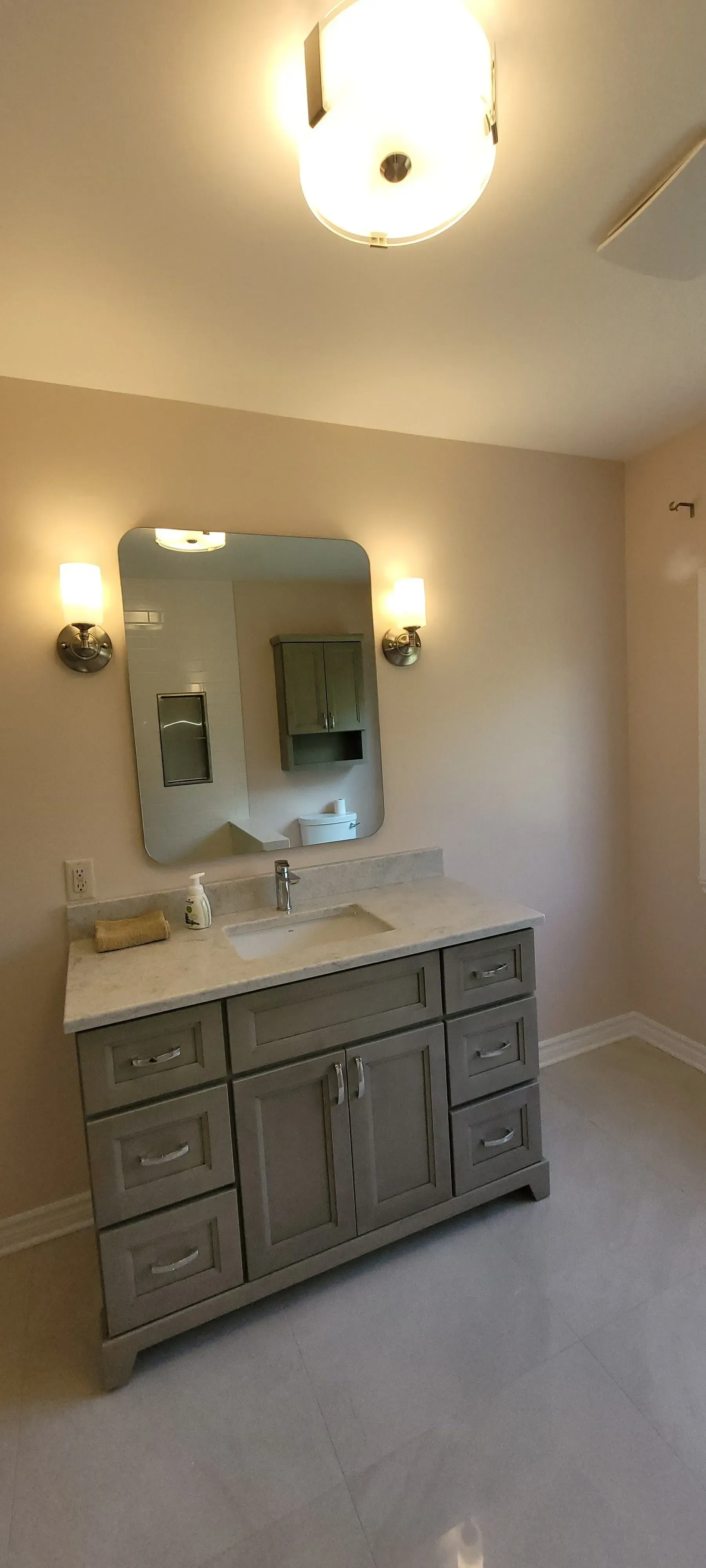 Meuble-lavabo de salle de bain avec double vasque, grand miroir, appliques murales et plafonnier.