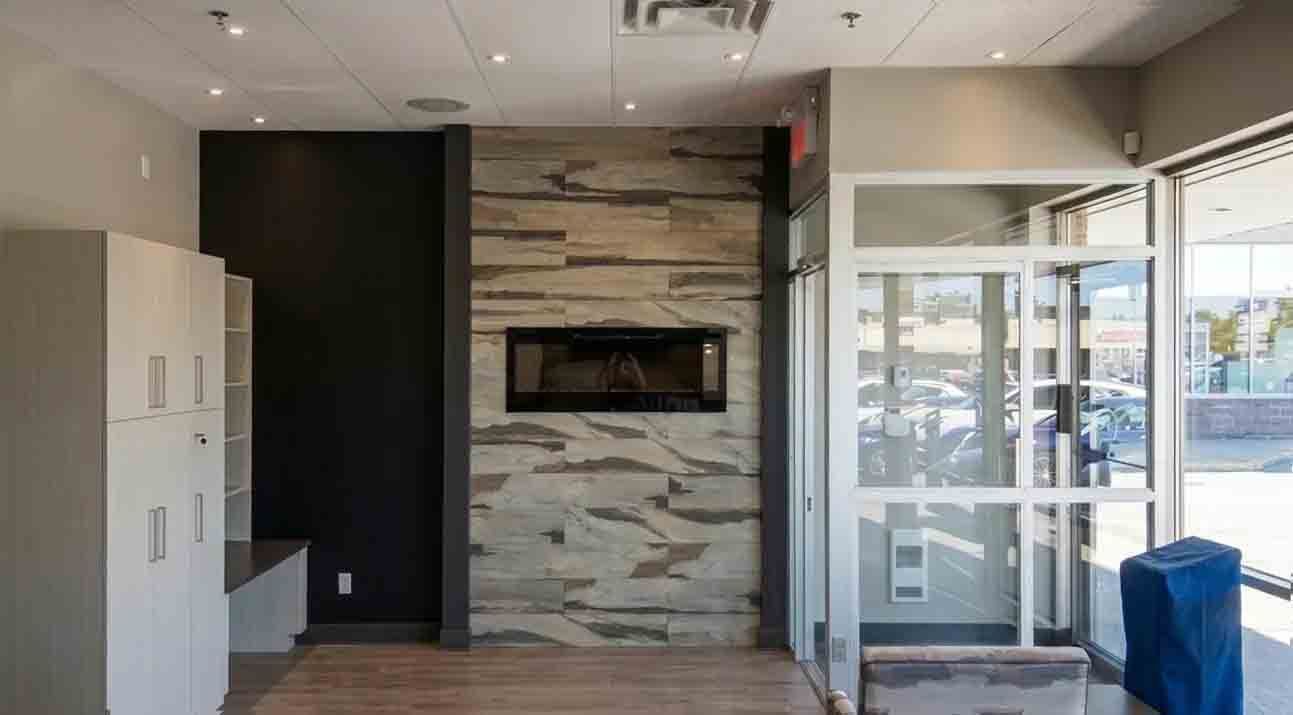 Intérieur moderne avec cheminée en pierre, mur d'accent noir et portes d'entrée vitrées laissant entrer la lumière du jour