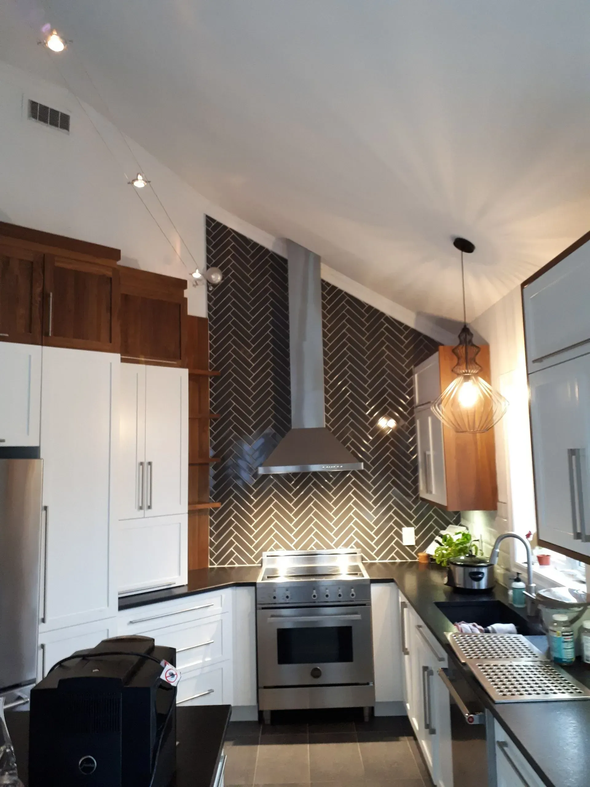 Cuisine moderne avec électroménager en inox, placards blancs et crédence en carrelage à chevrons