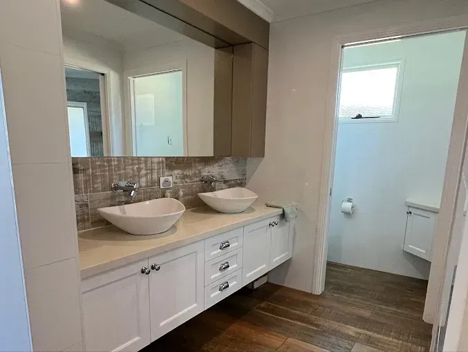 White double vanity with vessel sinks and mirror cabinets, leading to a separate toilet. — Rob Powell Plumbing Pty Ltd in Coraki, NSW