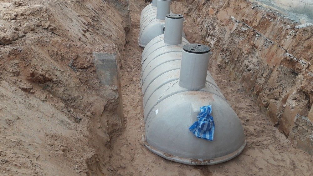 Three Gray Septic Tanks Are Installed in a Narrow, Excavated Trench — Rob Powell Plumbing Pty Ltd in Casino, NSW