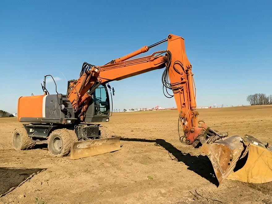 An Orange Excavator on Wheels Positioned in a Dry — Rob Powell Plumbing Pty Ltd in Coraki, NSW