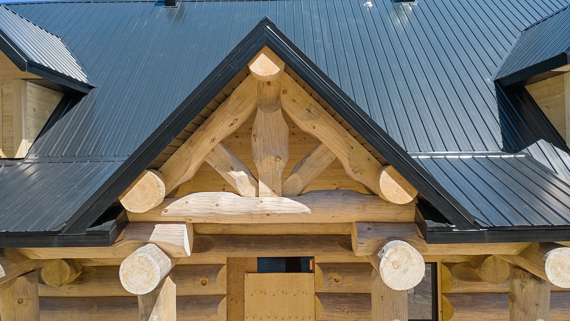 Log cabin roof with dark metal shingles and carved wooden gable details