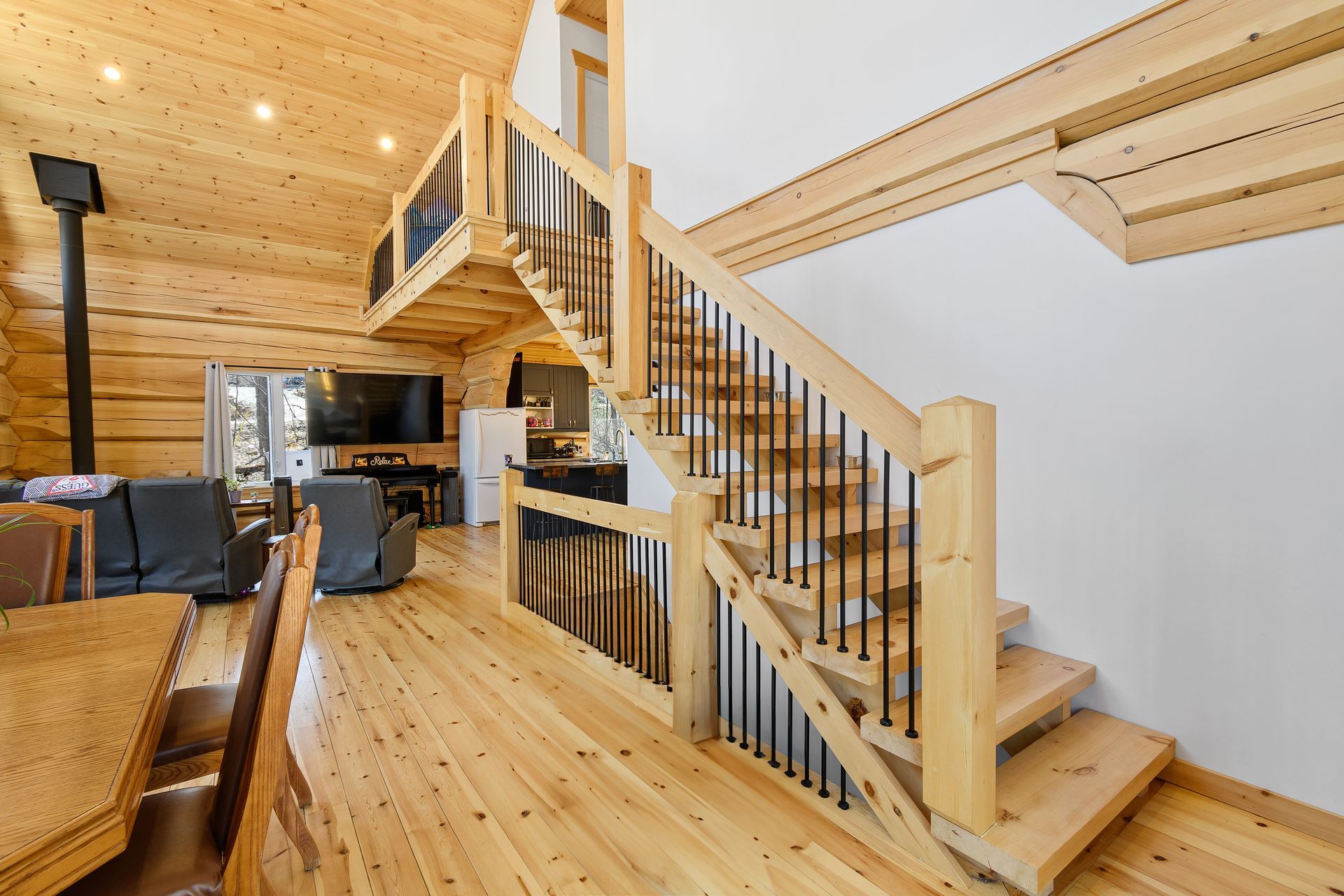 Wooden loft interior with stairs, railing, and open living area.