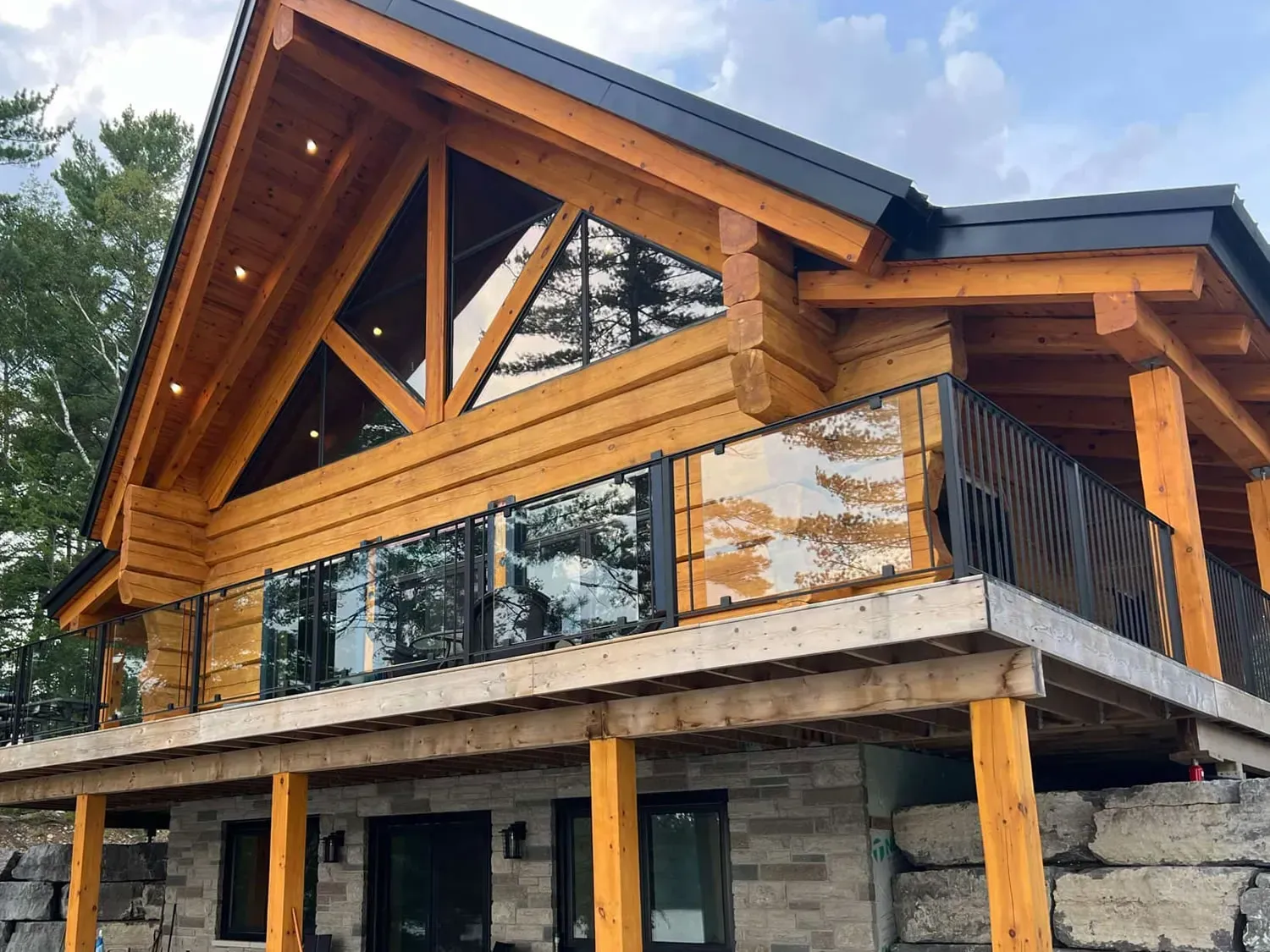 Modern two-story house with wood and stone exterior and large glass balcony.