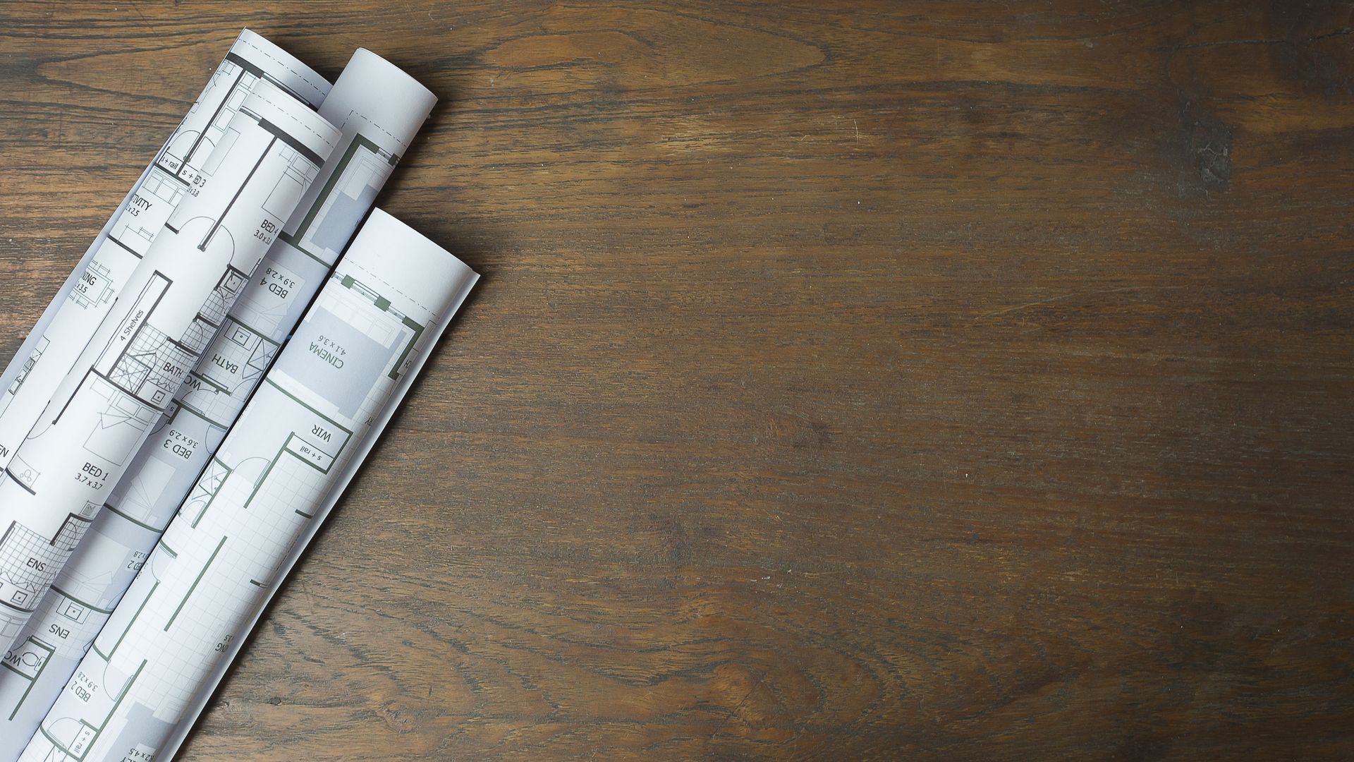 Rolled-up architectural blueprints on a wooden table