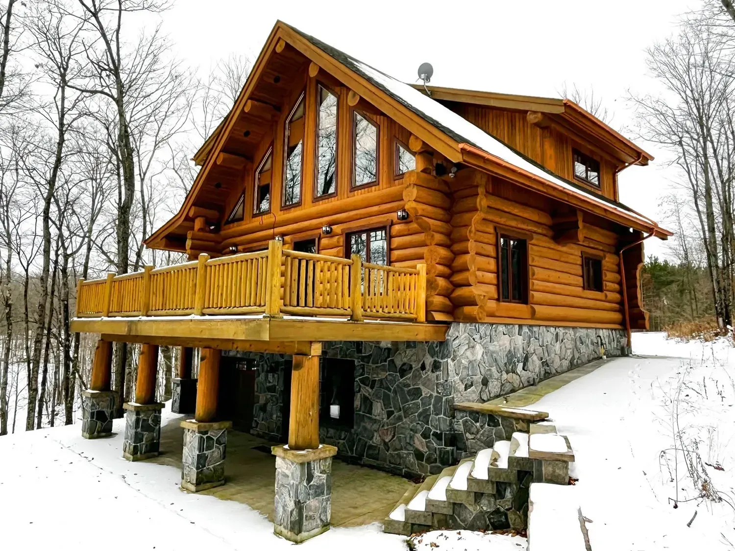 Log cabin on stone stilts with wooden deck in a snowy winter landscape