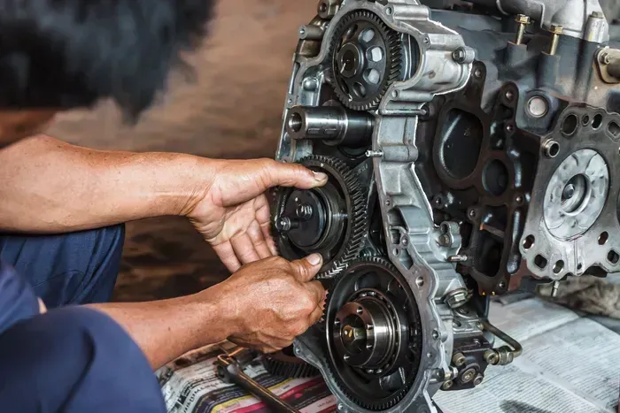 Hands assembling an engine's timing gear. Mechanics hands work on a car engine.