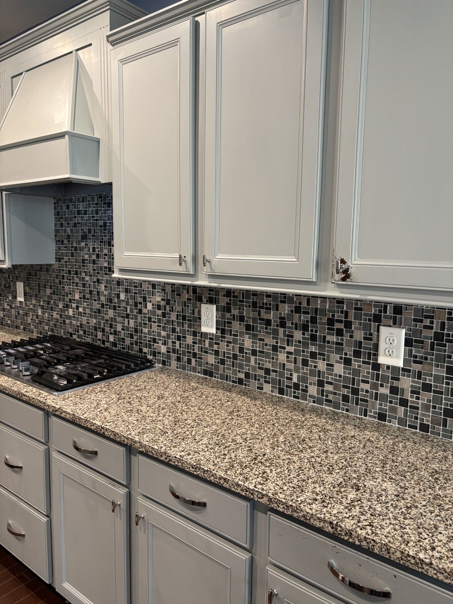 Modern kitchen with white cabinets, speckled countertop, mosaic backsplash, and a stovetop on the left  | Decatur, IL
