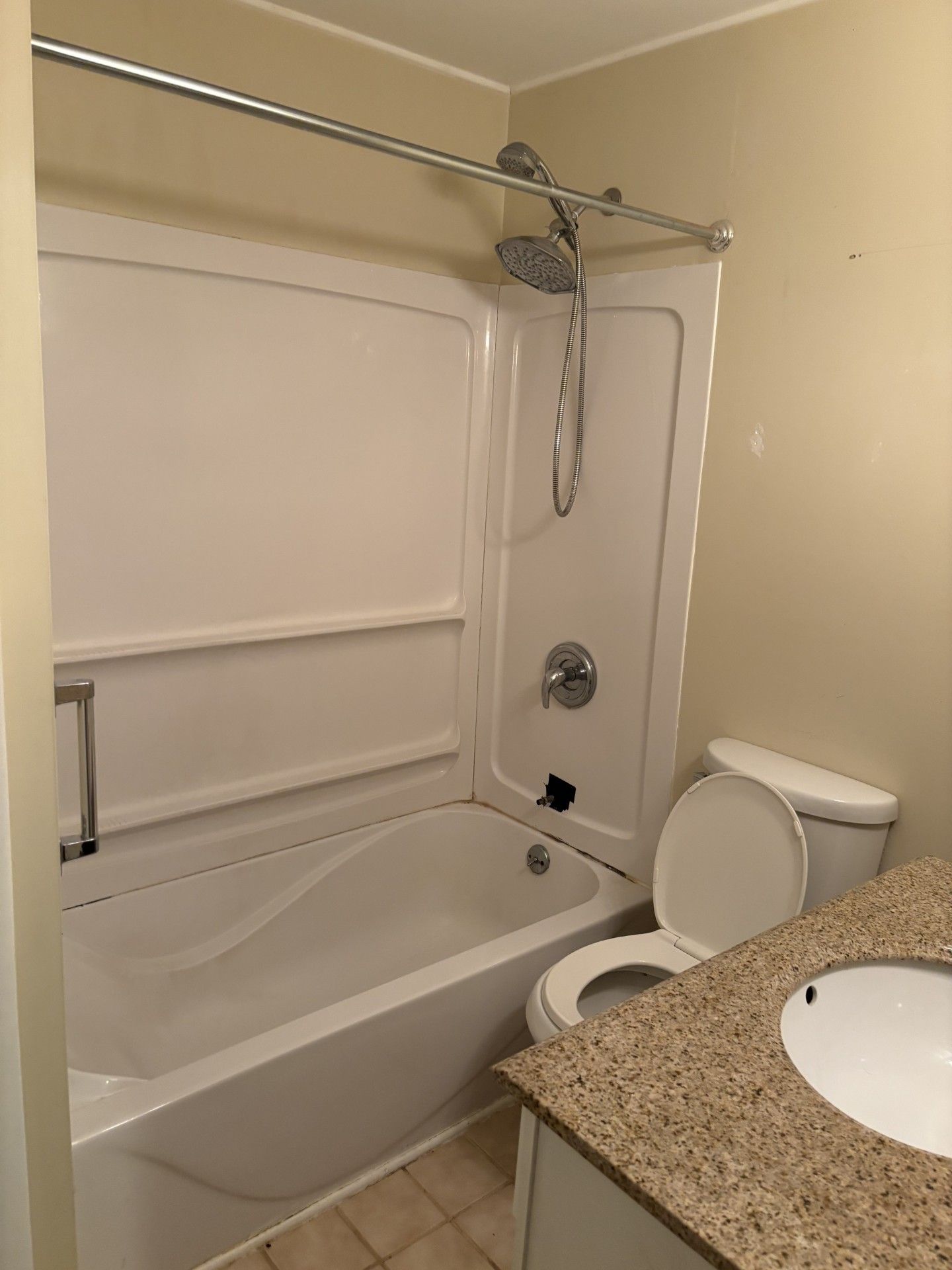 Small beige bathroom with tub-shower, toilet, sink, and granite countertop  | Decatur, IL
