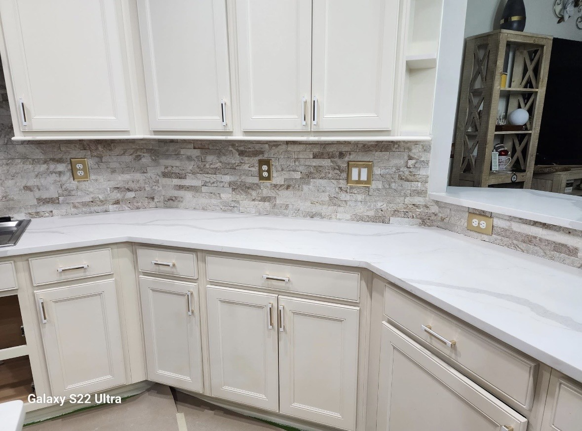 White kitchen with glossy cabinets, light marble backsplash, and curved white countertop.