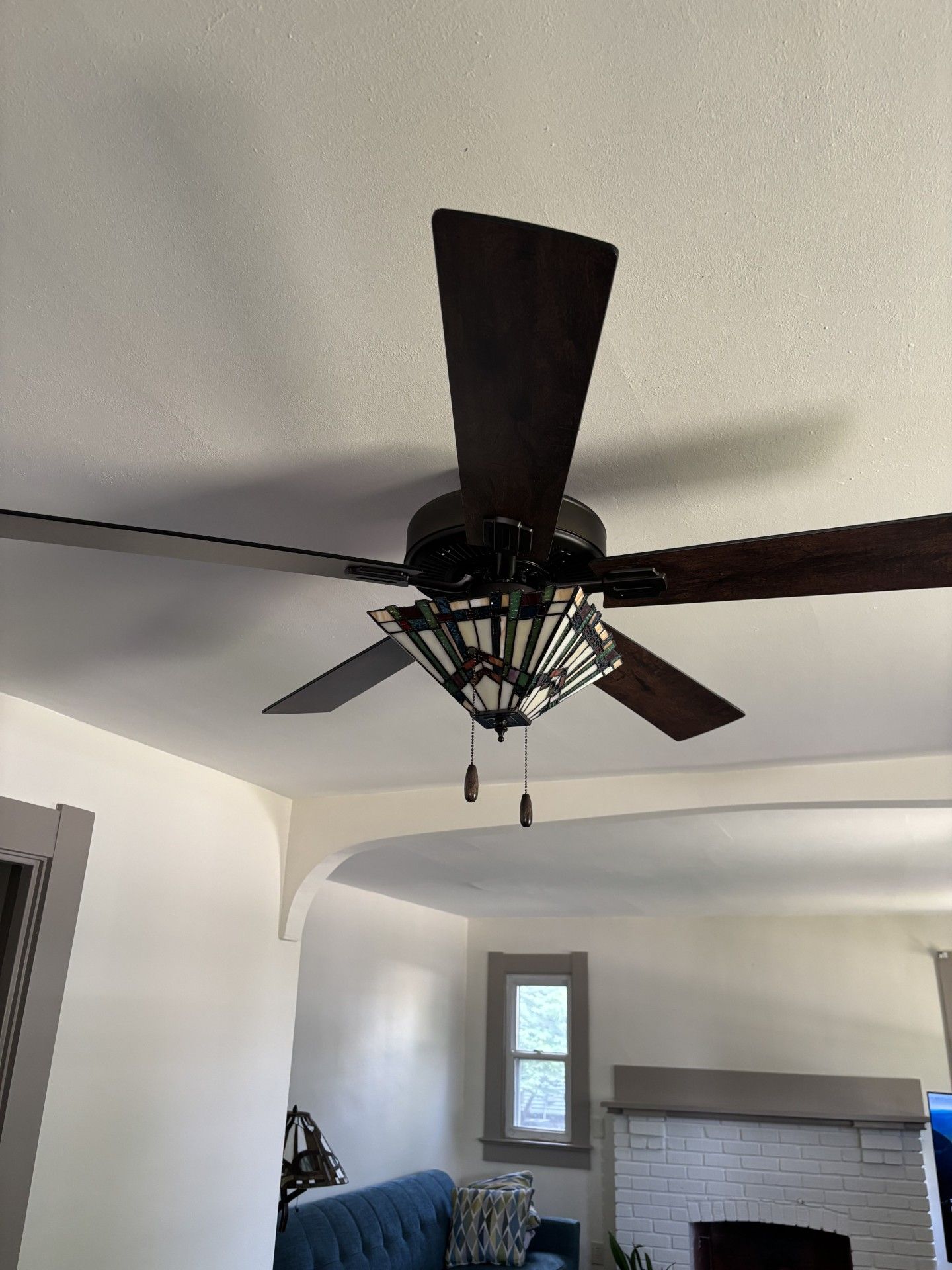 Living room with a dark ceiling fan, white walls, fireplace, and a small window | Decatur, IL
