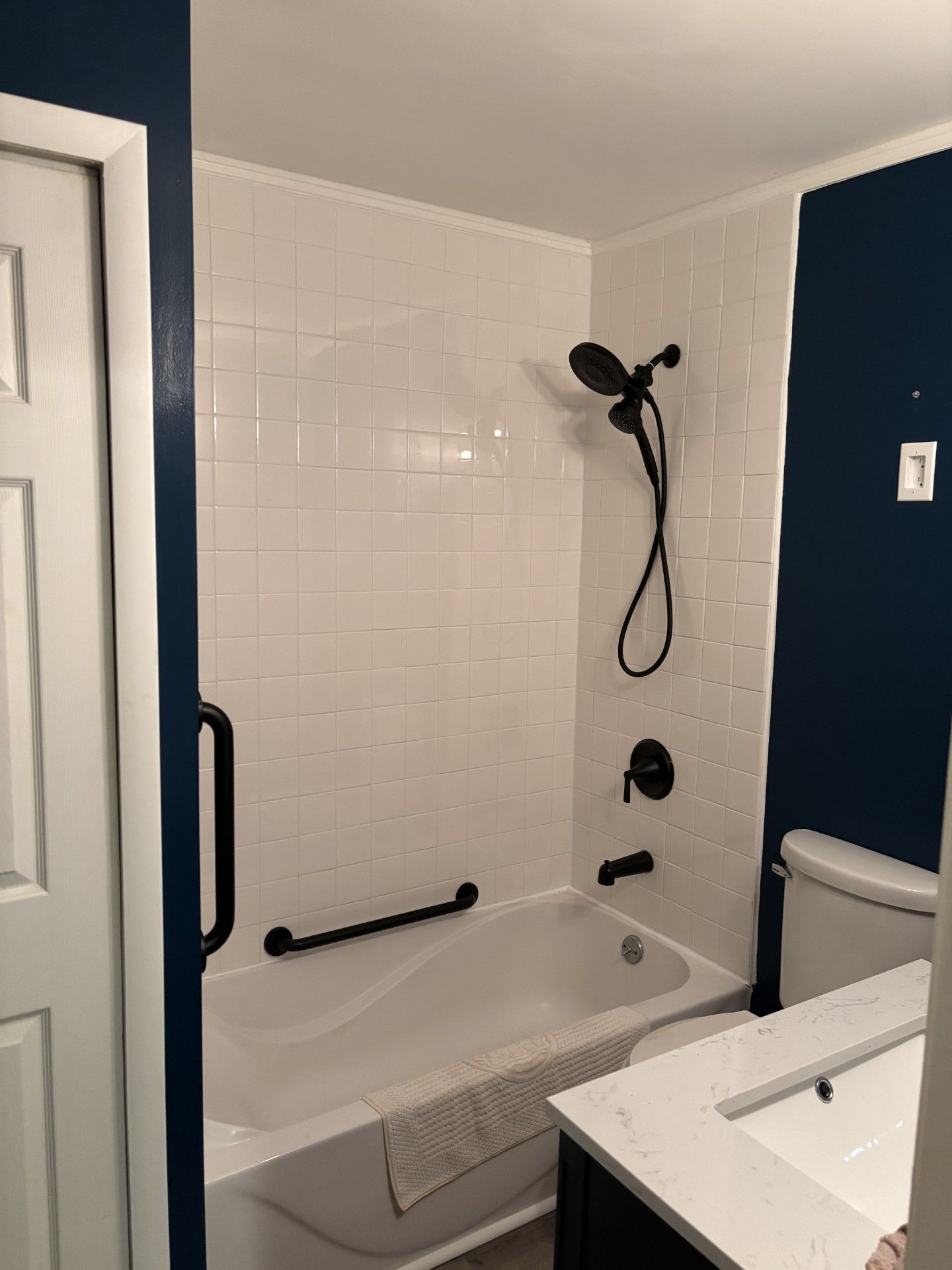 Small bathroom with a white tub, showerhead, and navy blue walls | Decatur, IL