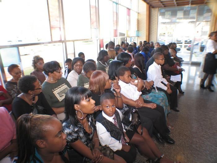 People seated in rows at an indoor public gathering, facing the front.