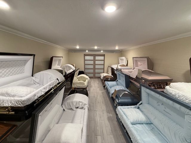 Room filled with mattresses and bed frames arranged in rows under ceiling lights