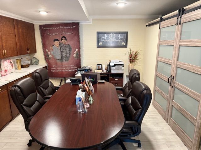 Conference room with oval wooden table, black chairs, wall art, cabinets, and frosted glass doors