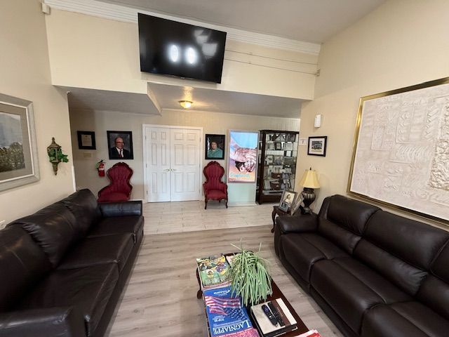 Living room with two dark leather sofas, coffee table, red chairs, wall art, and a wall-mounted TV