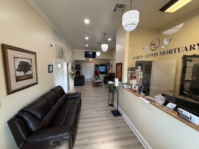 Office lobby with black leather sofa, reception desk, and hallway under warm ceiling lights