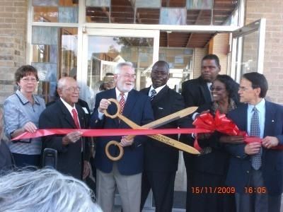 Ribbon-cutting ceremony with officials holding oversized scissors outside a building