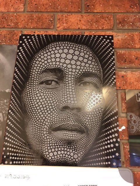 A black and white portrait of bob marley is on a brick wall